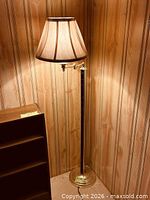 Full view of floor lamp showing wood column, brass base, pleated shade