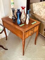 Three-quarter view of table showing leather top, cabriole legs, and drawer front