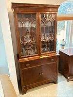 Full view of mahogany cabinet showing upper glazed doors and lower cupboard