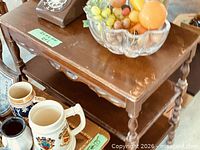Side view of mahogany three-tier side table with other objects on top (not included) showing finish wear