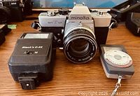 Front view of Minolta SR-T 101 camera with lens, Black’s G-22 flash, handheld exposure meter visible