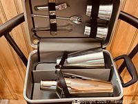 Open case showing shaker, tumblers and tools secured with straps