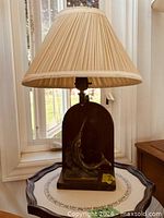 Full lamp showing wood base, marlin figure, beige pleated shade