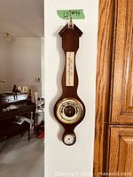 Full view of banjo-style wooden weather station hanging on wall