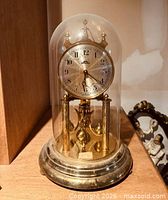 Front view of brass anniversary clock under glass dome