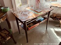 Full view of the wooden two-tier side table with items placed on top and shelf