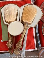 Two gold-tone hairbrushes and round hand mirror