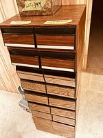 full view of tall drawer cabinet showing faux wood finish and multiple drawers