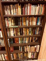 Full view of wooden bookcase loaded with books, shows overall structure and finish