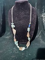 Full view of necklace on display bust showing bead arrangement and chain