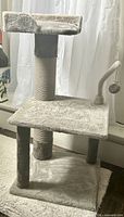 Full view of gray cat tree showing two levels, sisal post, hanging toy