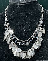 Full view of layered silver-tone necklace on display bust