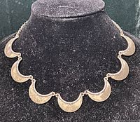 Full view of crescent bib necklace on display form