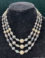 Full view of triple-strand necklace displayed on bust