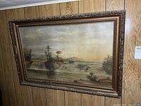 Framed landscape oil painting on wood-panelled wall