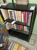 Front view of black three-shelf bookcase with books for scale