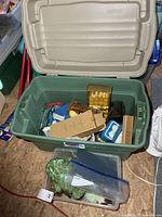 overview of green tote with assorted candles and decor inside plus additional clear bin with glass stones