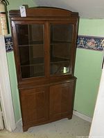 Front view of brown wooden corner cabinet showing full structure