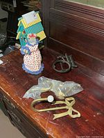 Group shot showing birdhouse, fabric mouse, brass towel ring, brass hooks in bag, black metal holder