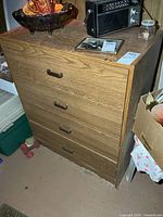 Front view of four-drawer laminate dresser showing pulls and wear on lower edge