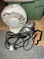Shark handheld vacuum and white tabletop fan with cords visible