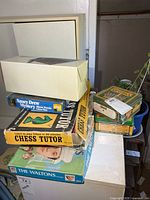 Stack showing Chess Tutor, Nancy Drew puzzle, The Waltons game, unidentified puzzle, Crayola tins