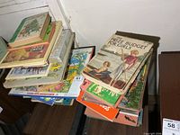 Two tall stacks of assorted vintage children’s books on table