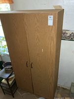 Front view of tall woodgrain pantry cabinet with two doors and handles
