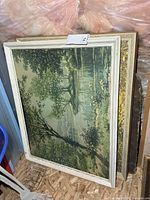 Two framed landscape prints leaning against wall