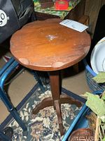 Full view of round top plant stand among surrounding items