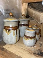 Front view of all four pottery canisters showing size variation and glaze