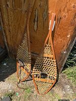 Full view of both wooden snowshoes leaning against wall