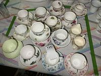 Overhead view of multiple floral teacups, saucers, creamer, sugar bowl