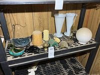 Shelf with assorted decor items including duck planter, black turtle, candles, milk glass vases, brass heron, globe shade