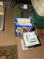 Overhead view showing ceramic bag vase, white lantern, and glass vases in plastic bin