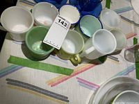 Group of mixed glass and enamelware mugs on table