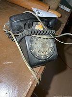 Top view of black rotary phone with handset and cords