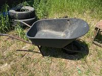 side view of black resin wheelbarrow showing metal frame and flat tire