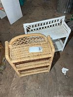 Natural wicker three-tier shelf front view with white two-tier shelf behind