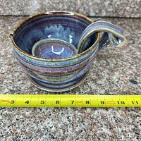 Bowl with ladle inside, tape showing diameter