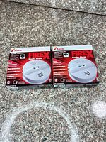 Front view of two sealed Kidde FireX PI2010 smoke alarm boxes