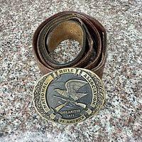 Coiled brown leather belt with NRA buckle front view