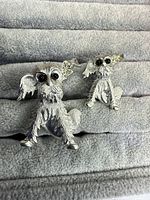 Both silver-tone puppy brooches front view