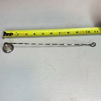 Full view of candle snuffer with tape measure showing 10 in length