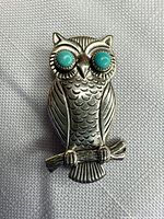 Front view of owl brooch showing turquoise eyes and feather detail