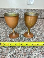 Front view of both copper goblets with tape for height reference