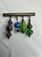 Front view of sterling bar brooch with four glass bead dangles