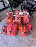 All seven red gasoline containers, funnel, siphon pump grouped