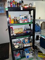 Front view of five-tier black plastic shelving unit filled with miscellaneous items (items not included)