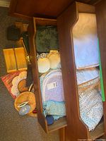 Drawer showing linens, Wedgwood dish, wooden bowls, shells and other items